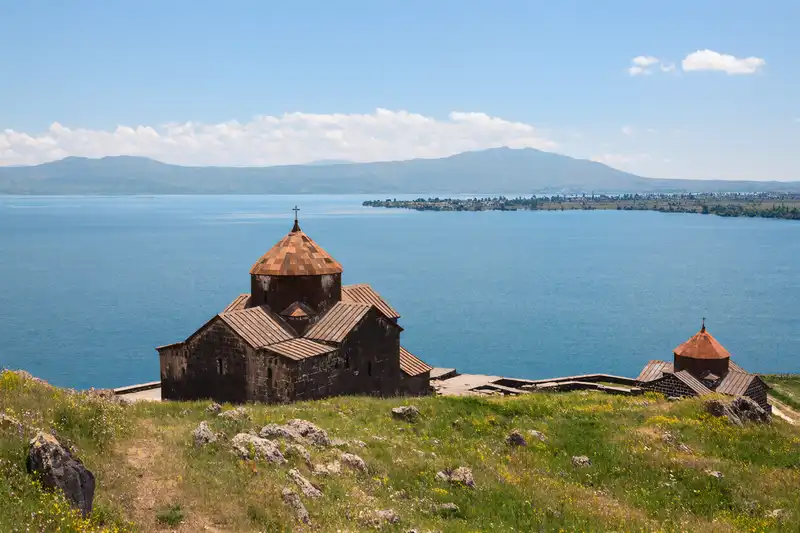The ancient, dark stone Sevanavank Monastery sits on a hilly peninsula overlooking the vast, deep blue expanse of Lake Sevan in Armenia, Gegharkunik Province, Armenia.