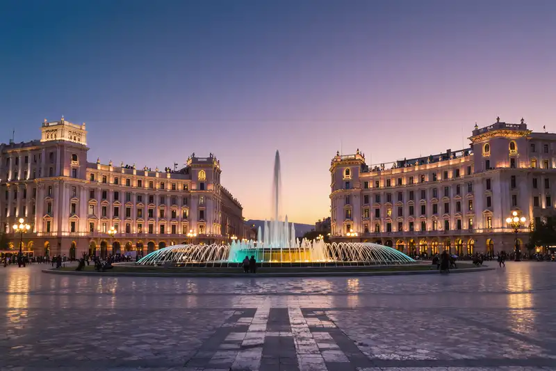 The magnificent, grand buildings made of pink and yellow tuff stone surrounding Republic Square in Yerevan are beautifully illuminated at twilight, with a musical fountain show in progress, Yerevan, Armenia.