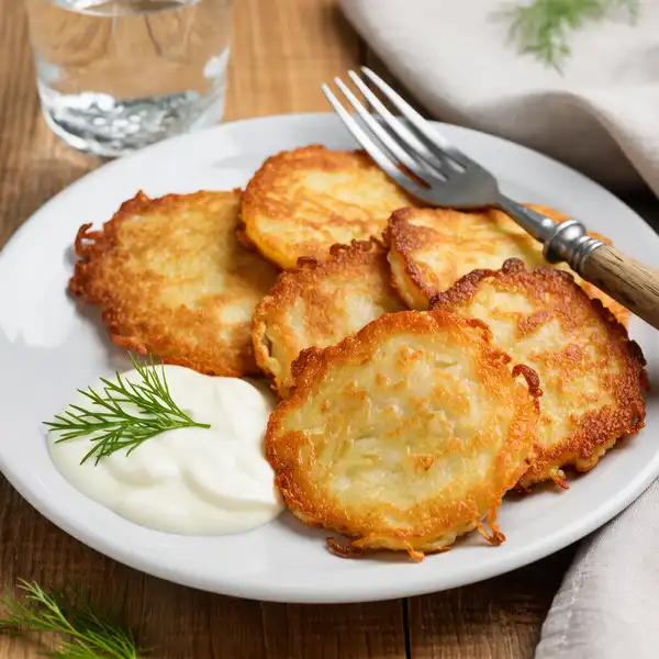 A stack of Belarusian Draniki (potato pancakes) with sour cream.