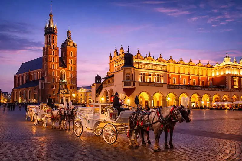 The Main Market Square in Krakow with St. Mary's Basilica and Cloth Hall at dusk.