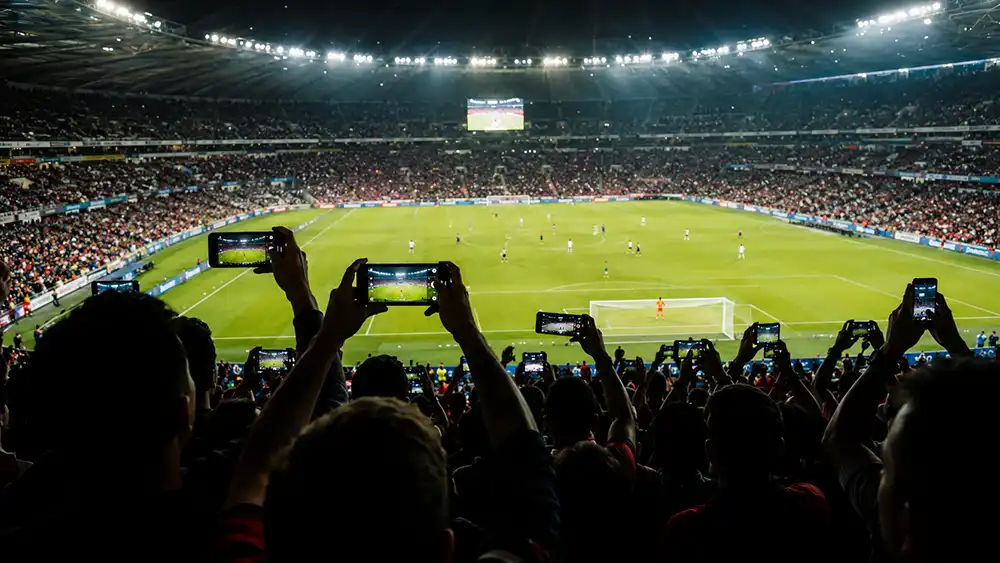 ClickRoam eSIM Review: Hands-On Test of a Premium Travel eSIM 3 Sports stadium crowd silhouette with fans holding up mobile phones during a football match