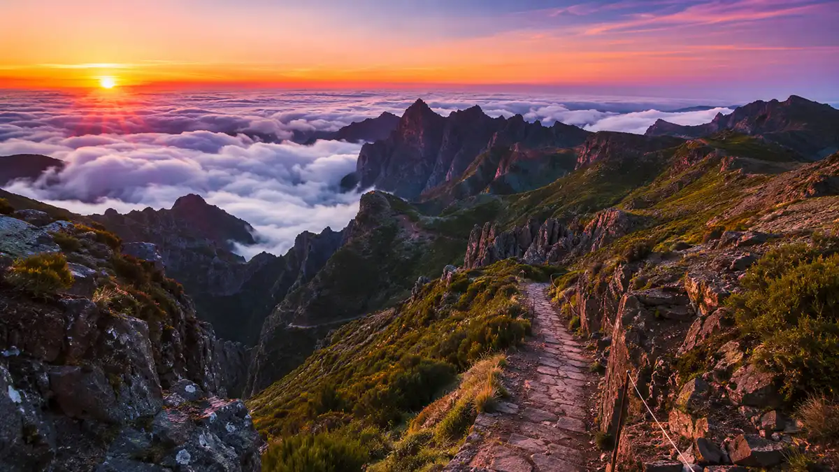 Panoramic view of Madeira Island's rugged mountain peaks above the clouds at sunrise