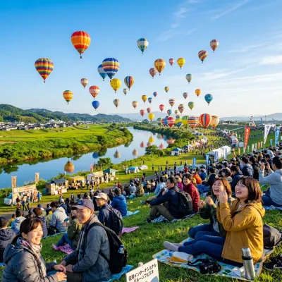 Dozens of vibrant hot air balloons lifting off into a clear sky over a riverbed in Saga.