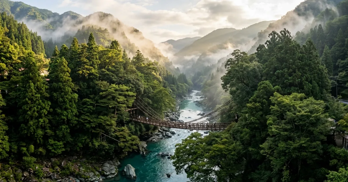 Scenic wide-angle view of the Iya Valley Kazurabashi vine suspension bridge across a lush mountain river gorge in Tokushima